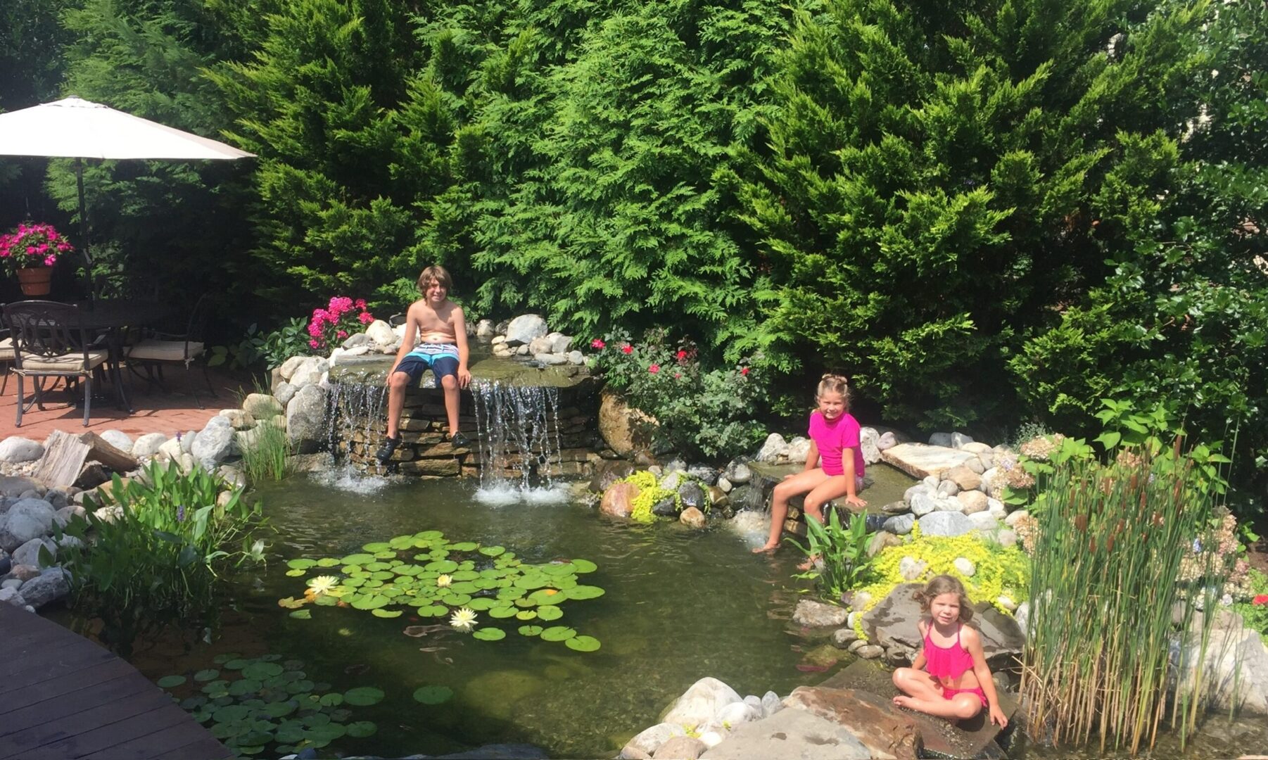 Two children sitting on a rock in the water.